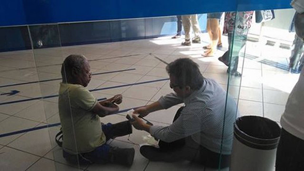 Gerente de banco senta no chão para atender cliente com deficiência, no Rio
