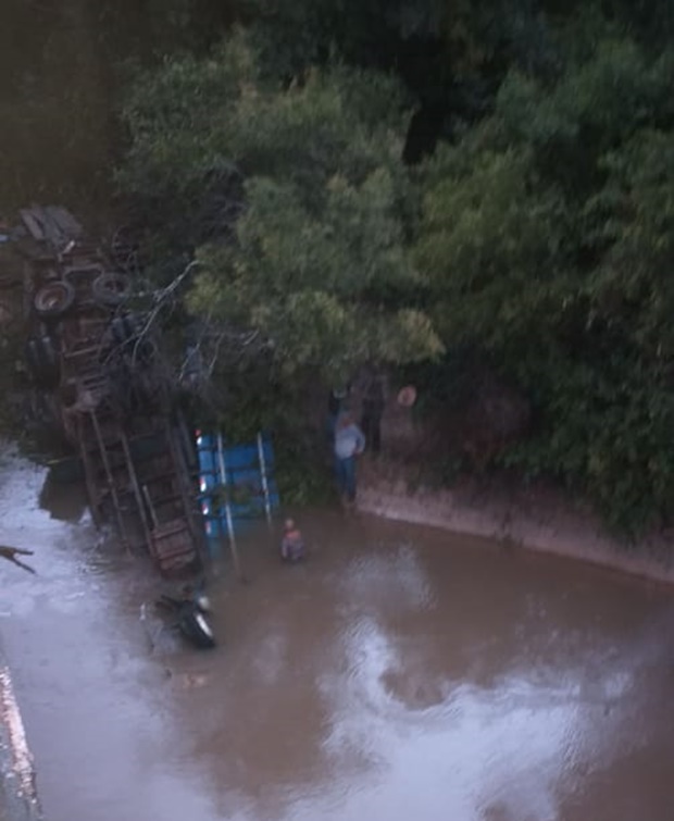 Motorista morre e dois acompanhantes ficam feridos após caminhão cair da ponte do Rio Feio